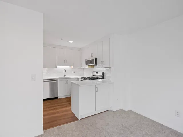 a kitchen with stainless steel appliances granite countertop a sink a stove a refrigerator and white cabinets