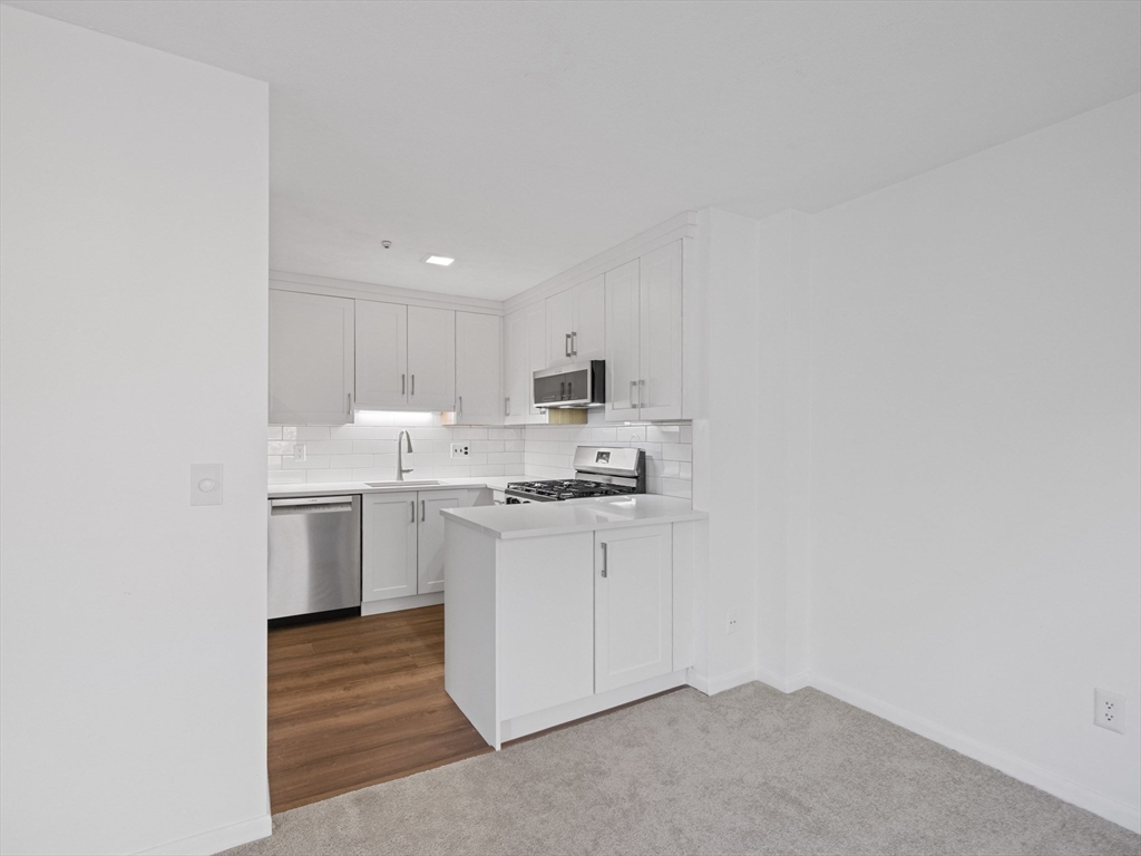 18 Concord Greene, Unit 6 Concord, MA 01742 - Photo 10 of 31 a kitchen with stainless steel appliances granite countertop a sink a stove a refrigerator and white cabinets