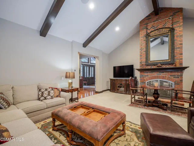 a living room with furniture a flat screen tv and kitchen view