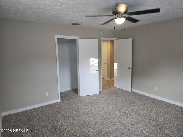 a view of an empty room and a ceiling fan window