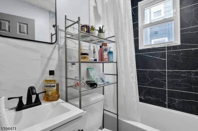 a living room with stainless steel appliances furniture a rug and a kitchen view