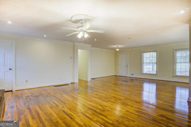 an empty room with wooden floor and windows