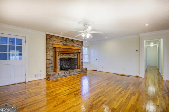 a view of an empty room with wooden floor fireplace and a window