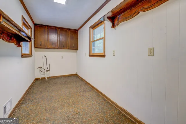 a view of an empty room with wooden floor and windows