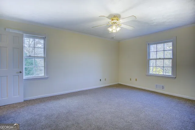 an empty room with windows and chandelier fan