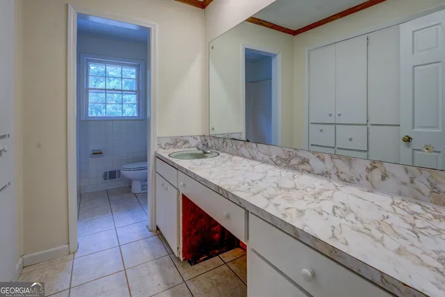 a bathroom with a granite countertop sink and toilet
