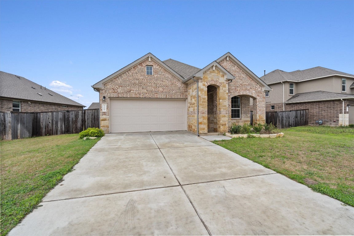 13908 Mcarthur Drive Manor, TX 78653 - Photo 1 of 1 a front view of a house with a yard and garage