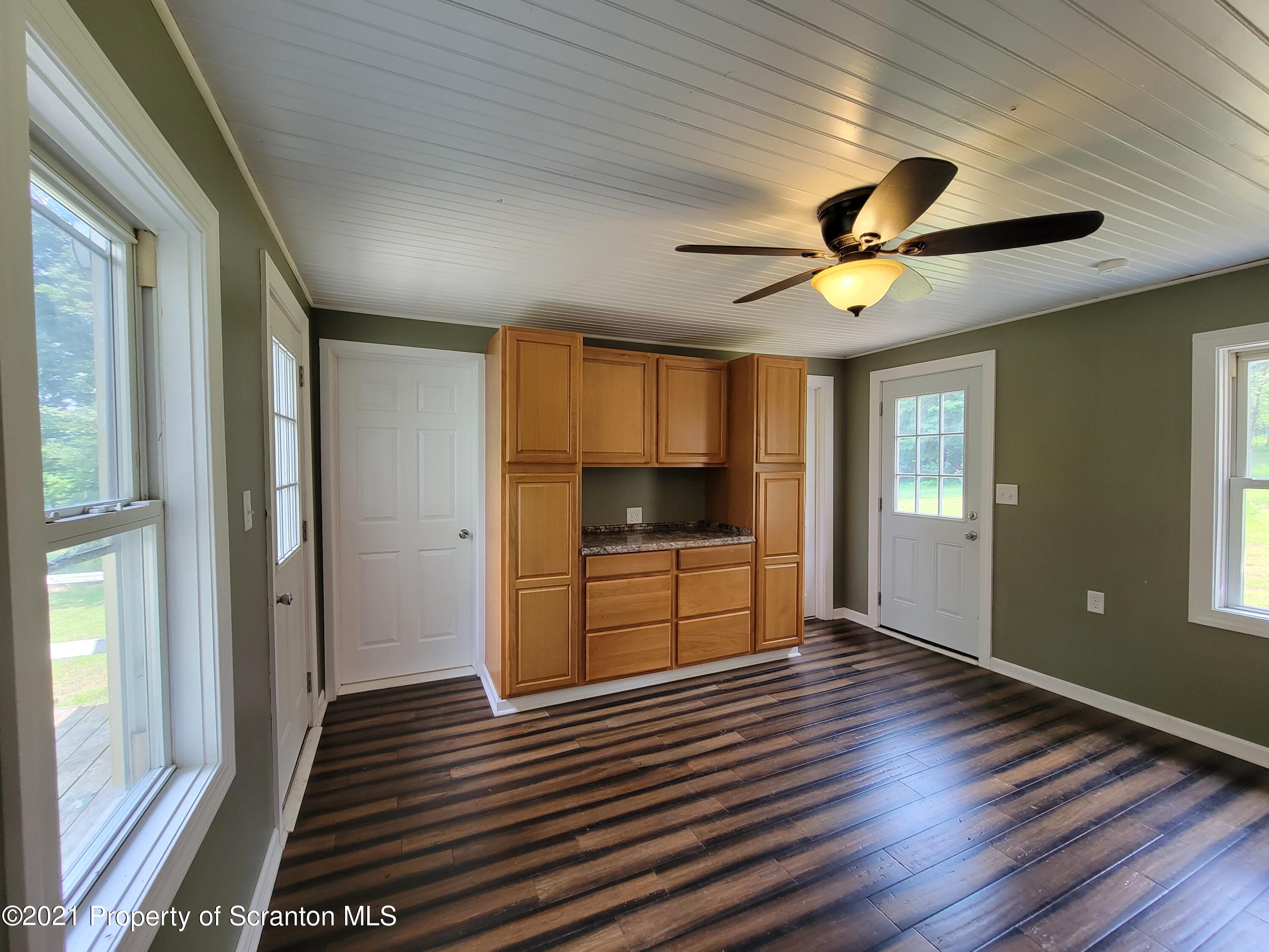 686 Wilcox Road Meshoppen, PA 18630 - Photo 12 of 30 a view of a livingroom with a flat screen tv wooden floor and a ceiling fan