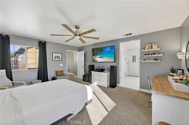 a bedroom with a large bed a flat tv screen and a chandelier
