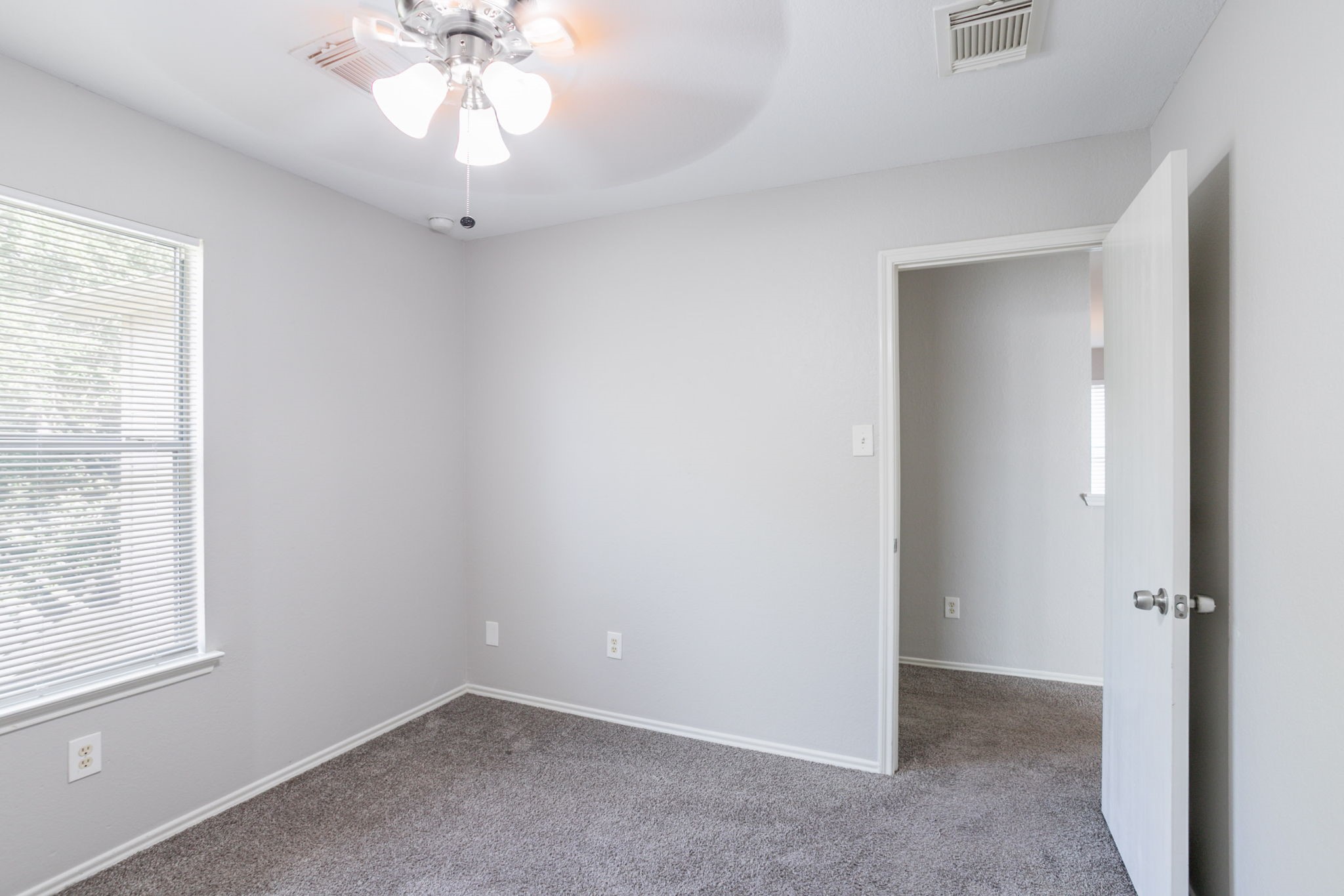 12026 Madison Oak Street Houston, TX 77038 - Photo 26 of 39 an empty room with a chandelier fan and windows