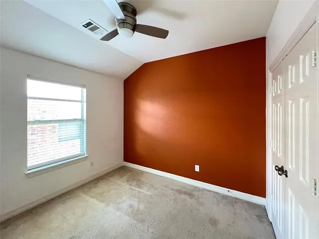 an empty room with windows and fan