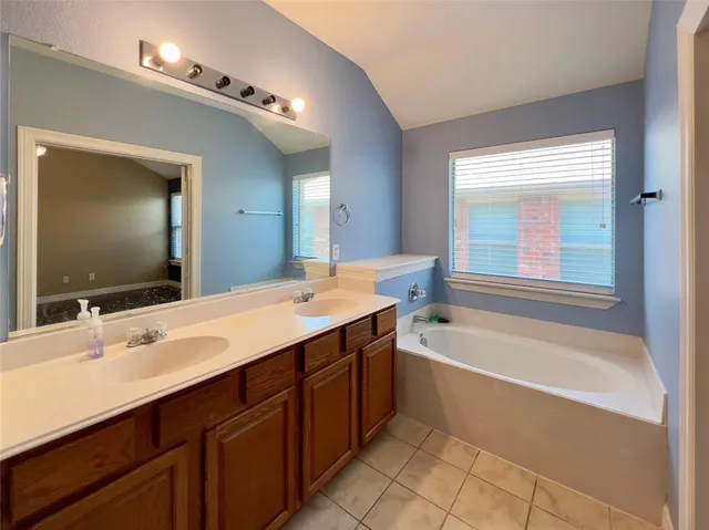a spacious bathroom with a tub sink and mirror