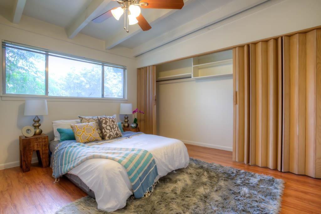 Bedroom with light wood-style flooring, vaulted ceiling with beams, and ceiling fan