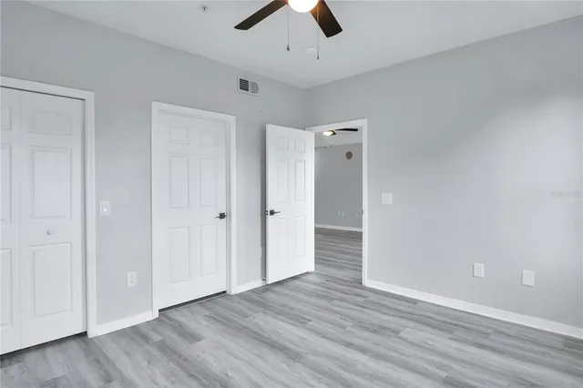 an empty room with wooden floor and ceiling fan