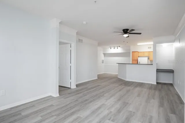 an empty room with wooden floor cabinet and windows