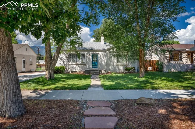 a front view of a house with a yard and tree