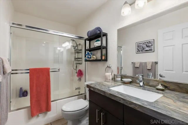 a bathroom with a granite countertop sink mirror vanity and toilet
