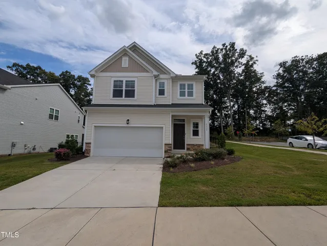 a front view of a house with a garden and trees