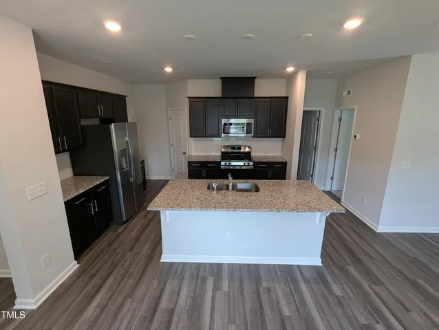 a kitchen with stainless steel appliances a refrigerator a sink a stove a microwave and wooden floor