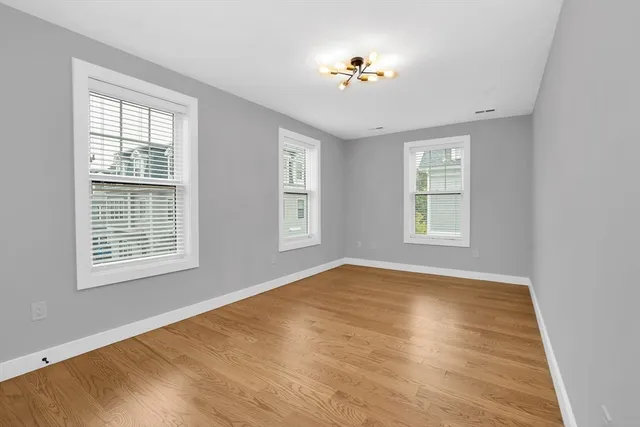 a view of an empty room with a window and wooden floor