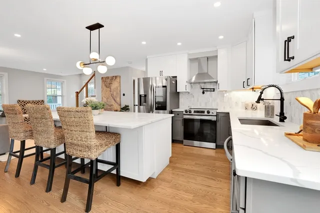 a kitchen with stainless steel appliances kitchen island granite countertop a table chairs sink and cabinets