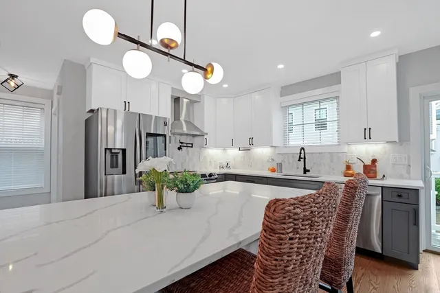 a kitchen with stainless steel appliances granite countertop a refrigerator a sink dishwasher a dining table and chairs with wooden floor