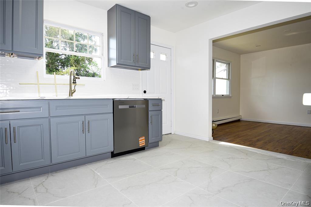 65 Bluebird Lane Plainview, NY 11803 - Photo 11 of 28 a kitchen with white cabinets a sink and a window