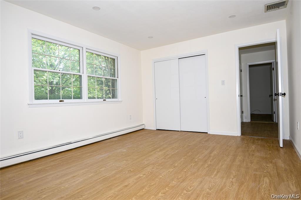 65 Bluebird Lane Plainview, NY 11803 - Photo 13 of 28 an empty room with wooden floor and windows