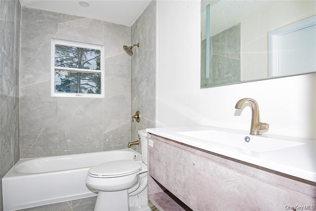 65 Bluebird Lane Plainview, NY 11803 - Photo 15 of 28 a bathroom with a sink a toilet and a bathtub