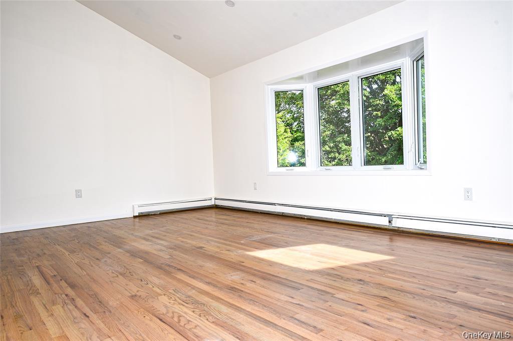 65 Bluebird Lane Plainview, NY 11803 - Photo 6 of 28 a view of an empty room with wooden floor and a window