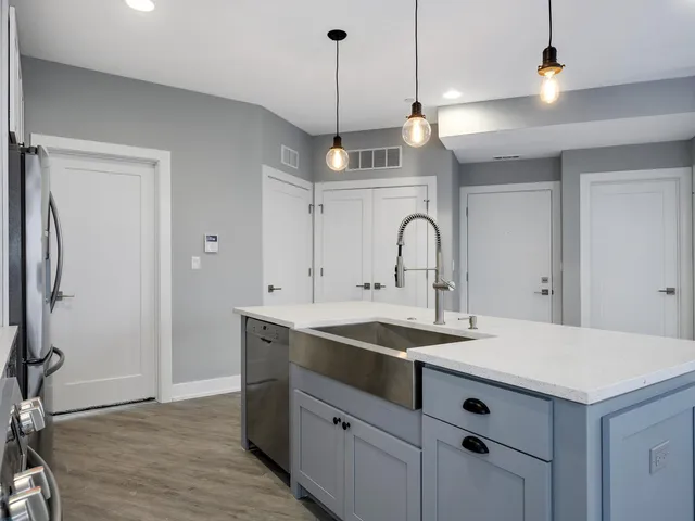 a large kitchen with stainless steel appliances a large counter top a stove a sink and a refrigerator