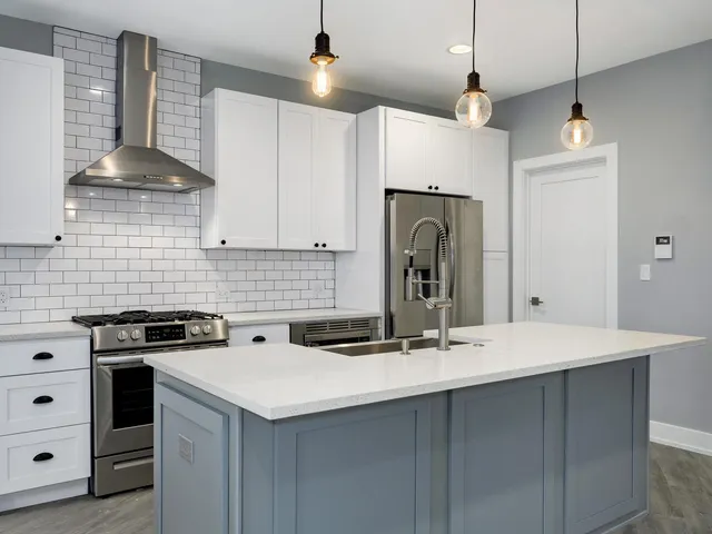 a kitchen with stainless steel appliances granite countertop a stove a sink dishwasher and a refrigerator with wooden floor