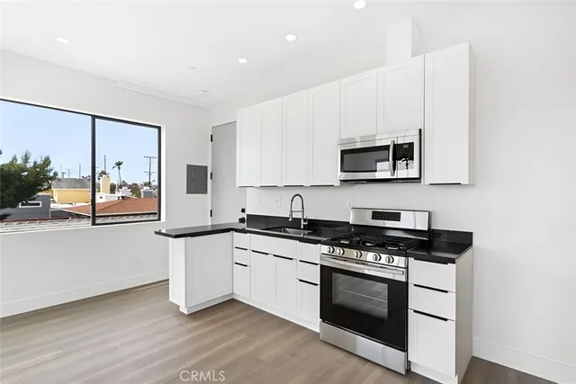 a kitchen with granite countertop a stove a sink and a microwave