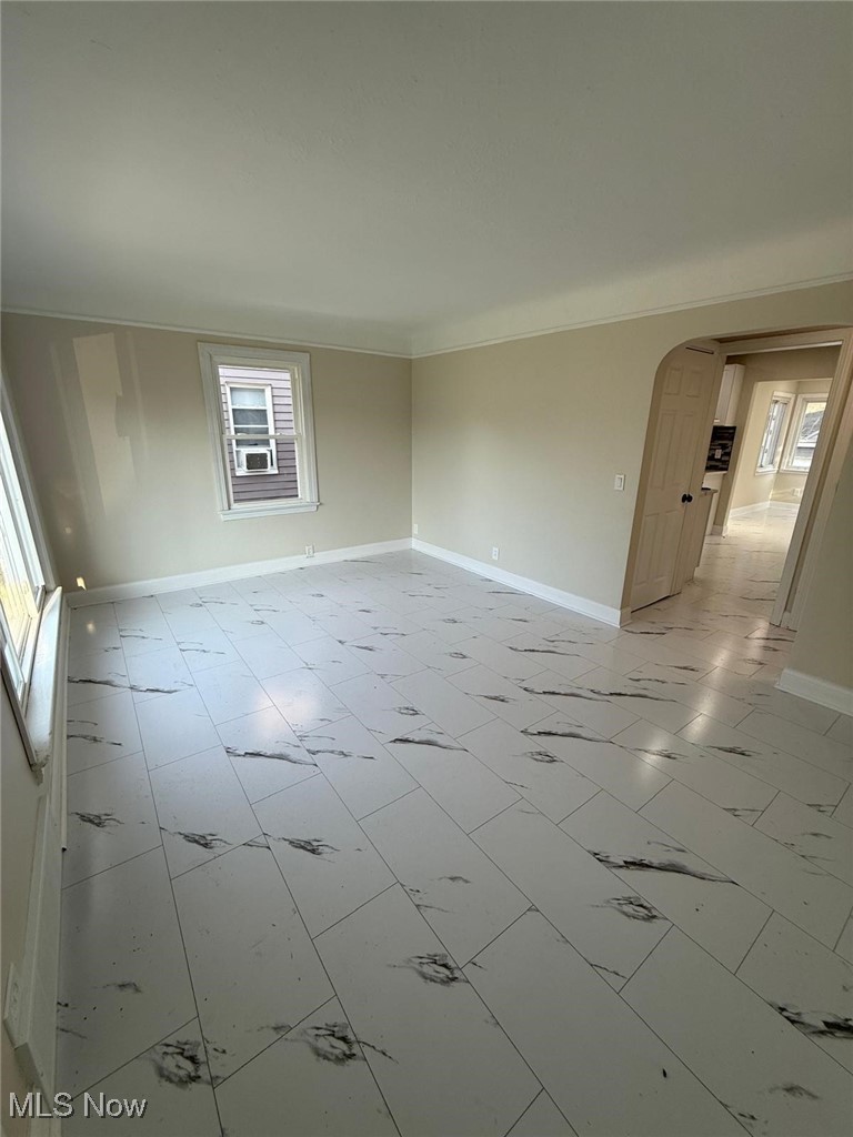 15410 Turney Road Maple Heights, OH 44137 - Photo 7 of 46 Empty room featuring arched walkways, light marble finish floors, and crown molding