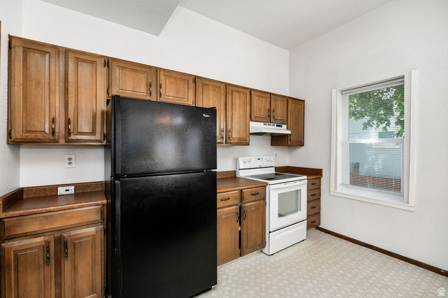 299 West Center Street, Unit 2 Logan, UT 84321 - Photo 12 of 46 Kitchen featuring ample wood cabinetry, laminate countertops, a built-in range hood, an electric range, and a window