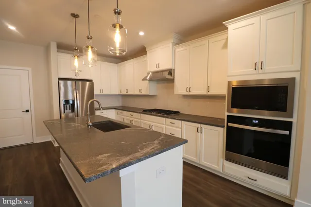 a kitchen with kitchen island granite countertop a sink a stove and cabinets