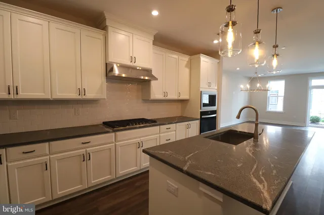a kitchen with stainless steel appliances granite countertop a sink a stove and a wooden floors
