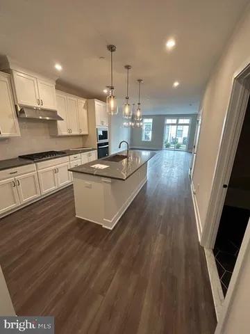 a large kitchen with cabinets a sink and dishwasher a stove with wooden floor