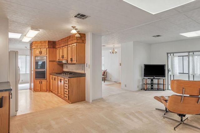 a living room with furniture a flat screen tv and kitchen view
