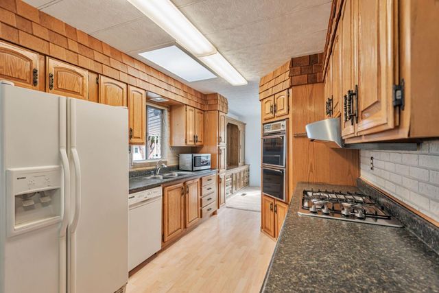a kitchen with stainless steel appliances granite countertop a refrigerator a stove and a sink