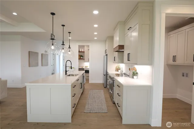 a large white kitchen with a sink and dishwasher with a large kitchen island