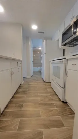 a view of a kitchen with white cabinets and wooden floor