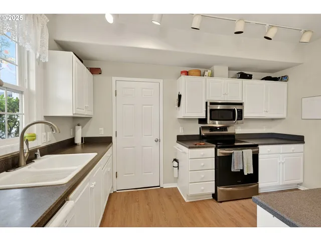 a kitchen with stainless steel appliances granite countertop a sink and white cabinets