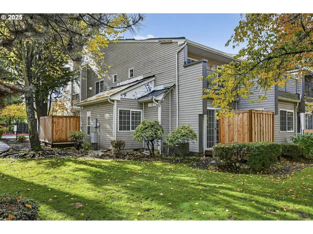 a backyard of a house with plants and large tree