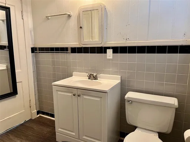 a bathroom with a toilet a sink and wooden floor
