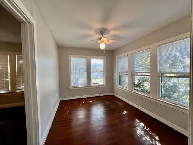 a view of empty room with wooden floor and fan