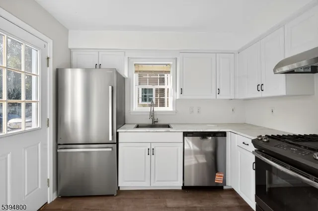 a kitchen with stainless steel appliances white cabinets and a refrigerator