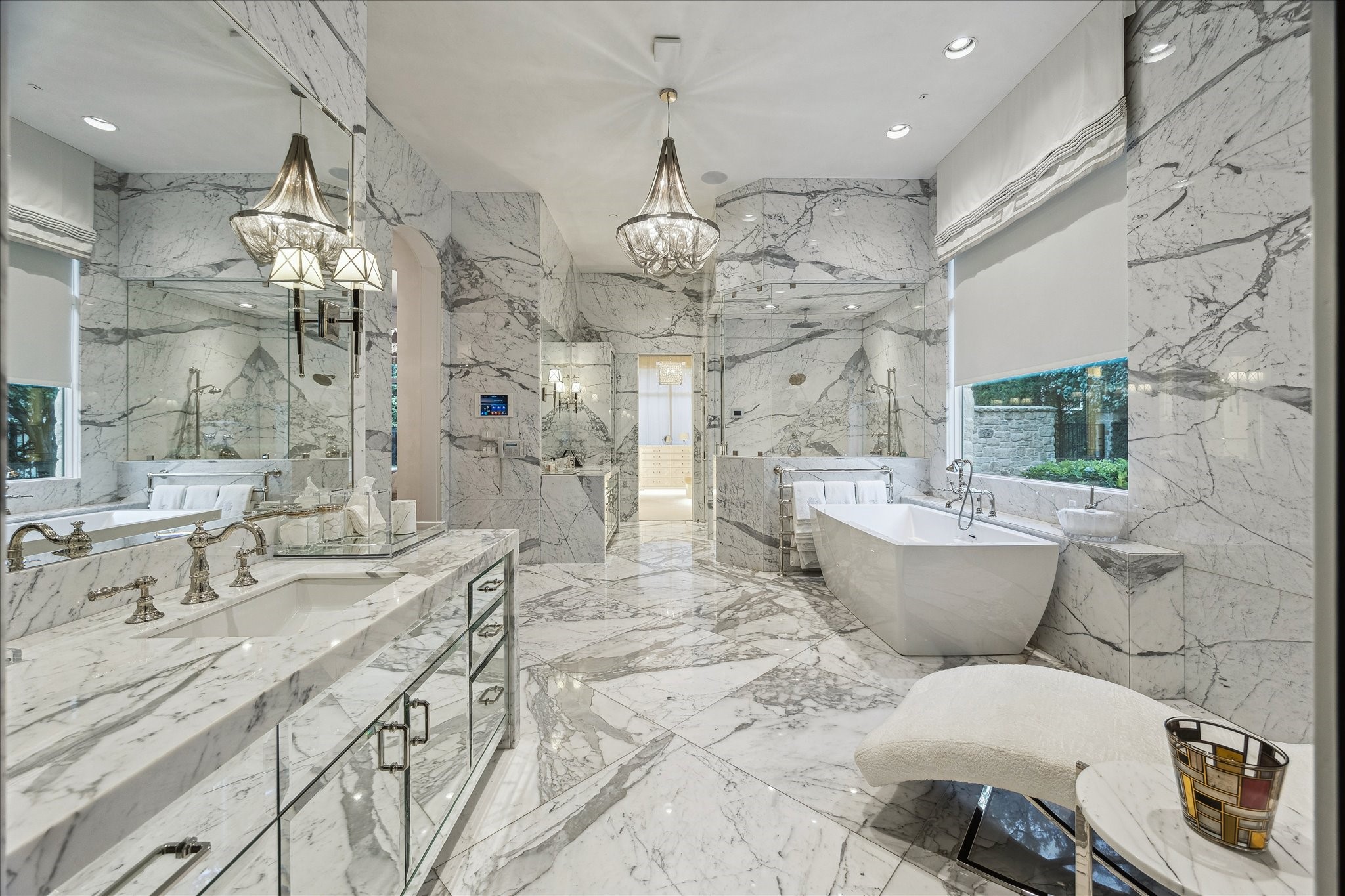 220 Merrie Way Lane Houston, TX 77024 - Photo 24 of 50 Inspired by Villa d’Este on Lake Como, the primary bathroom showcases Calacatta marble at every turn—from book-matched full-slab walls to custom-cut tile floors and baseboards. A crystal chandelier sets an elegant tone above dual vanities with waterfall marble countertops, mirrored cabinetry, and polished nickel fixtures. Additional highlights include dual water closets, Segreto-plastered ceilings, a walk-in shower, and BainUltra jetted tub.
