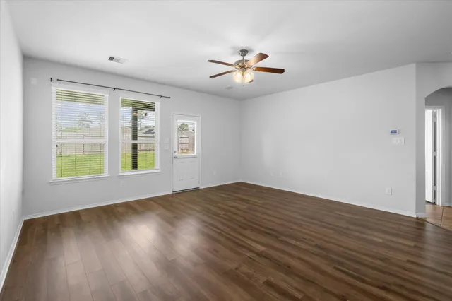 a view of empty room with wooden floor and fan