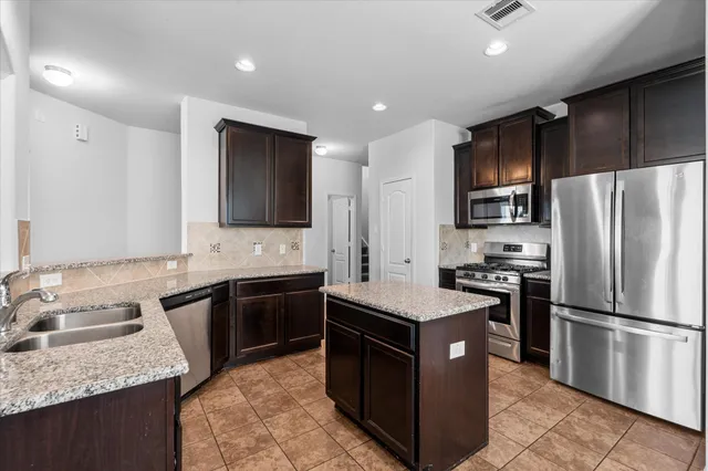 a kitchen with stainless steel appliances granite countertop a stove a sink dishwasher a refrigerator and a oven